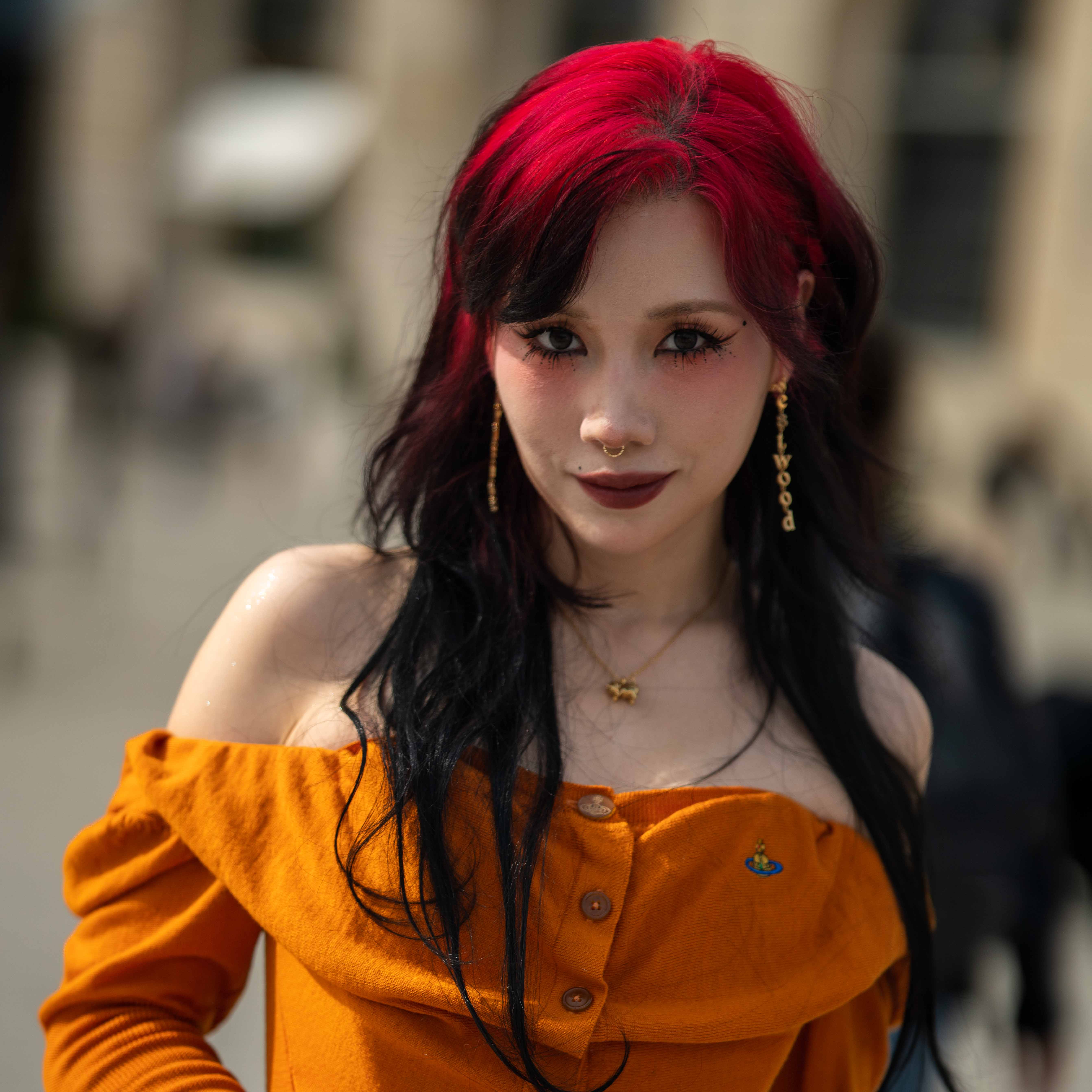 Riisa Naka 仲里依紗 Street Style At Andreas Kronthaler For Vivienne Westwood SS24 Paris Fashion Week.  The Japanese actress is wearing an orange top, leopard print bag and gold accessories.