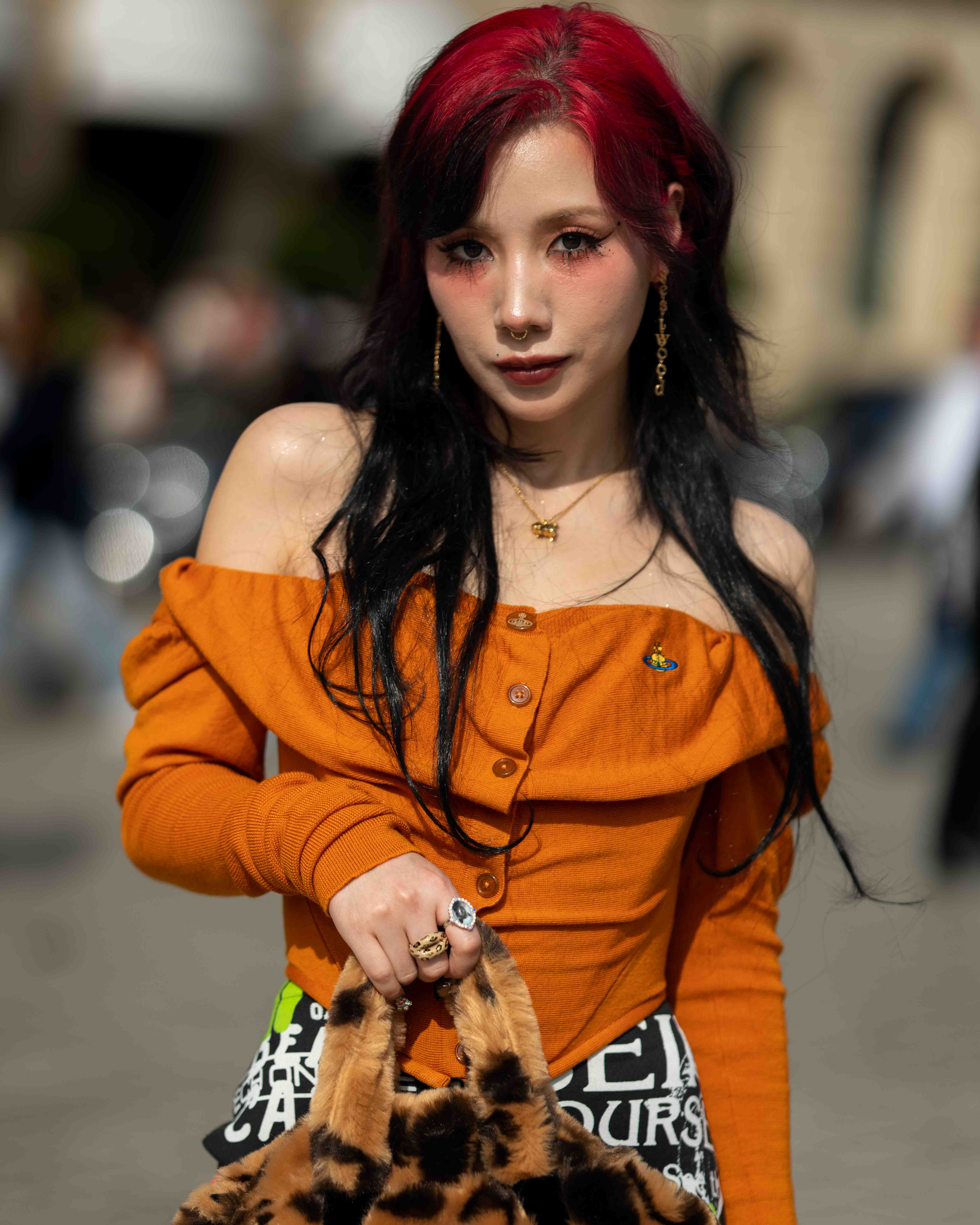 Riisa Naka 仲里依紗 Street Style At Andreas Kronthaler For Vivienne Westwood SS24 Paris Fashion Week.  The Japanese actress is wearing an orange top, leopard print bag and gold accessories.